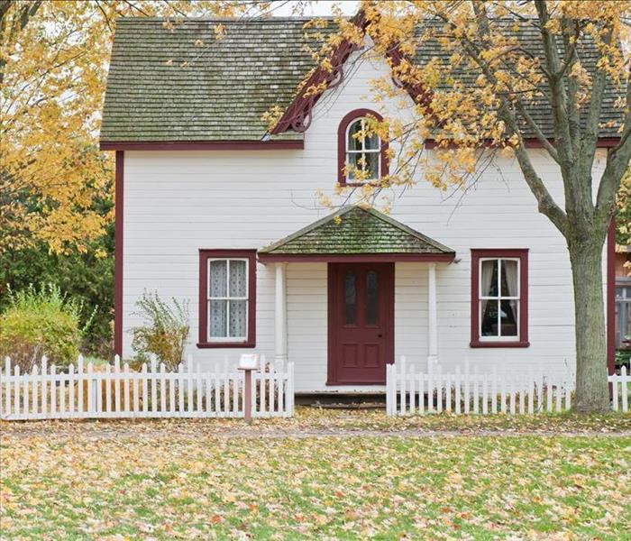 white home with red trim and a forest behind it